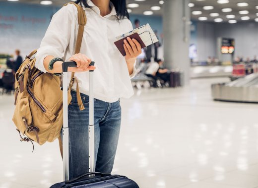 Eine Frau mit Koffer und Reisedokumenten
